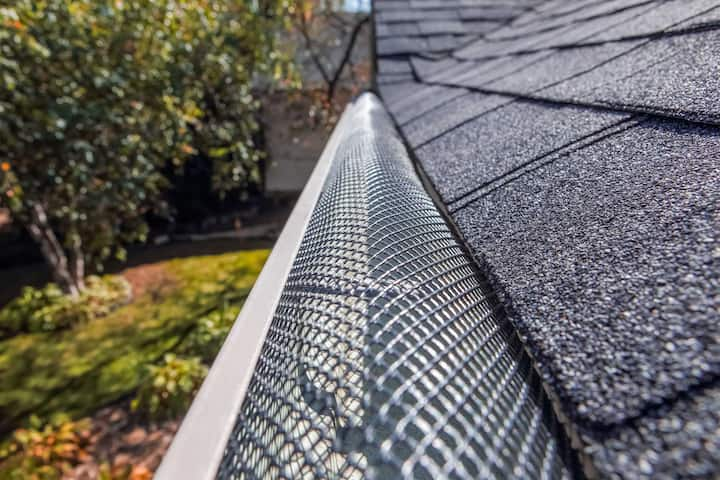 A contractor demonstrating the effectiveness of a gutter guard to a potential client in Dallas